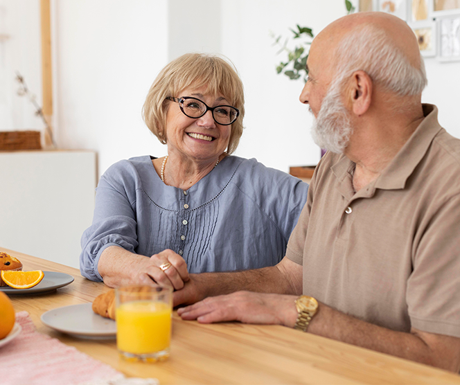 älteres glückliches Ehepaar sitzend am Tisch