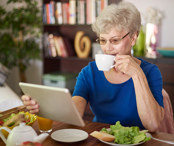 Ältere Frau nutzt Tablet als Hilfe, um Heizung zu steuern